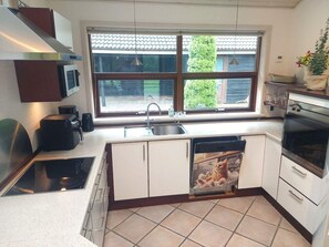 A modern kitchen with a built-in dishwasher, a stove, and a window with a view of the outside. - 8 Person Holiday Home in Oksbol (Oksbol)