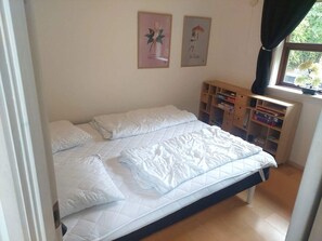A bedroom with a bed, pillows, a wooden shelf with books, and two framed pictures on the wall. - 8 Person Holiday Home in Oksbol (Oksbol)