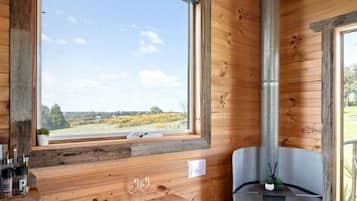 Un intérieur en bois avec une grande fenêtre, une cheminée, une table et une chaise.
