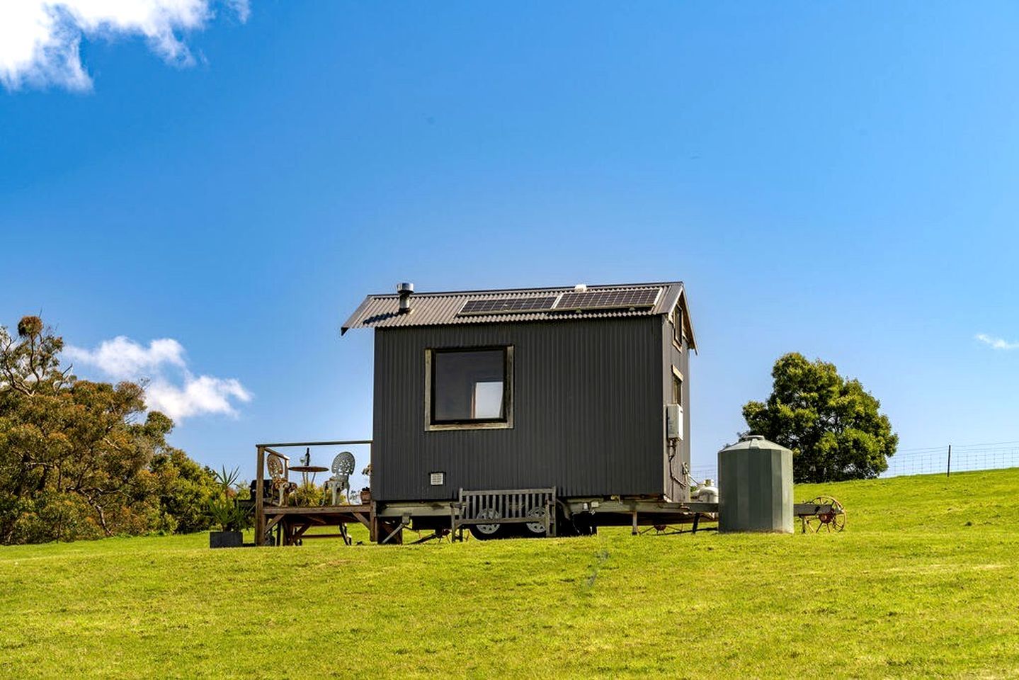 A small, single-story cabin with a metal exterior, a window, and a solar panel on the roof.