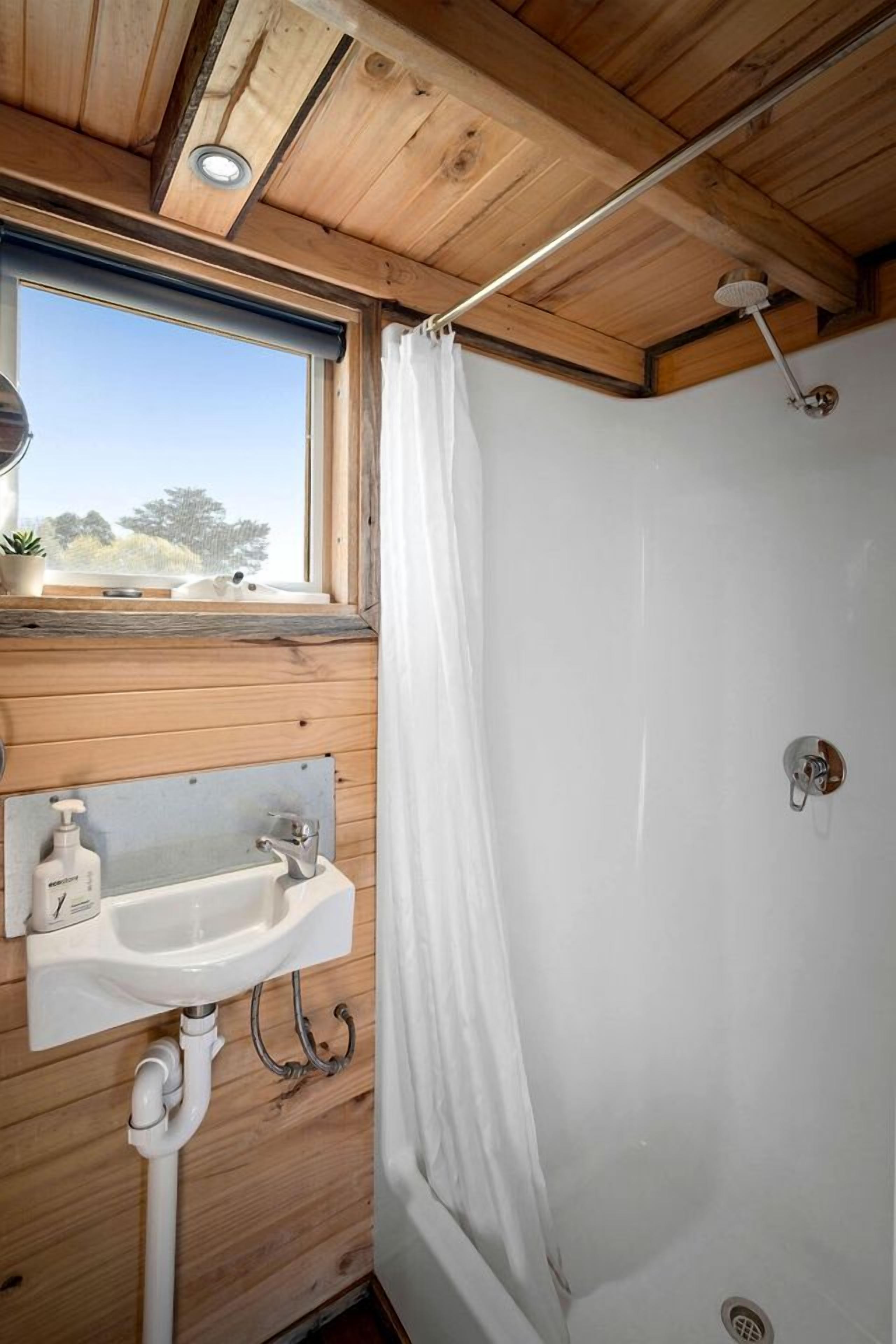 Un intérieur en bois avec une fenêtre, un évier et une douche.