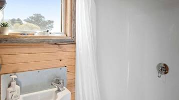 Un intérieur en bois avec une fenêtre, un évier et une douche.