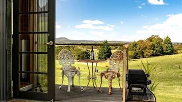 A wooden deck with two ornate chairs, a grill, and a gas cylinder.