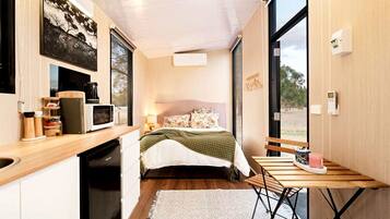 A compact bedroom with a bed, bedside table, and a window.