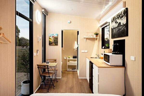 A compact kitchen with a dining area, a microwave, and a small refrigerator.