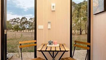 A room with a wooden table and two chairs, a door leading outside, and a wall-mounted light fixture.