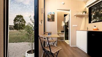 A modern kitchen with a wooden table and chairs, a black dishwasher, and a view of the outdoors.