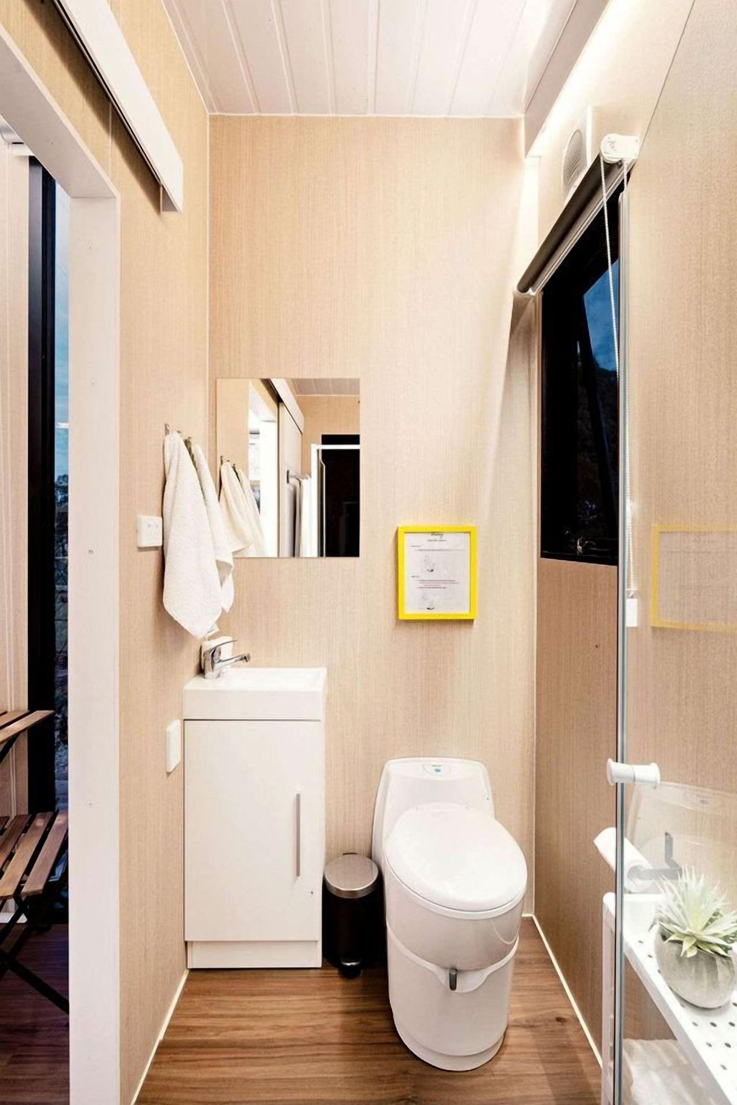 A modern bathroom with a white sink, toilet, and a glass shower enclosure.