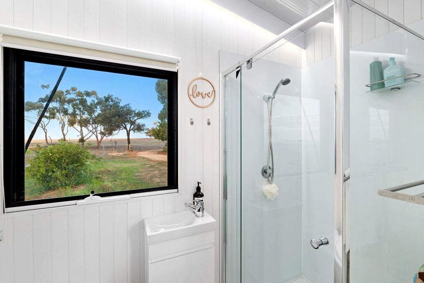 Une salle de bain avec une fenêtre, une douche et un lavabo.