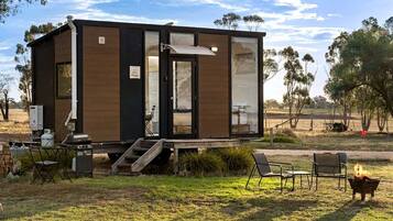 Una cabana moderna de planta baixa amb terrassa, seients a l'aire lliure i una xemeneia.