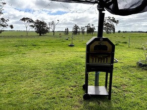 A rural landscape with a wooden structure, possibly a shed, in a grassy field.