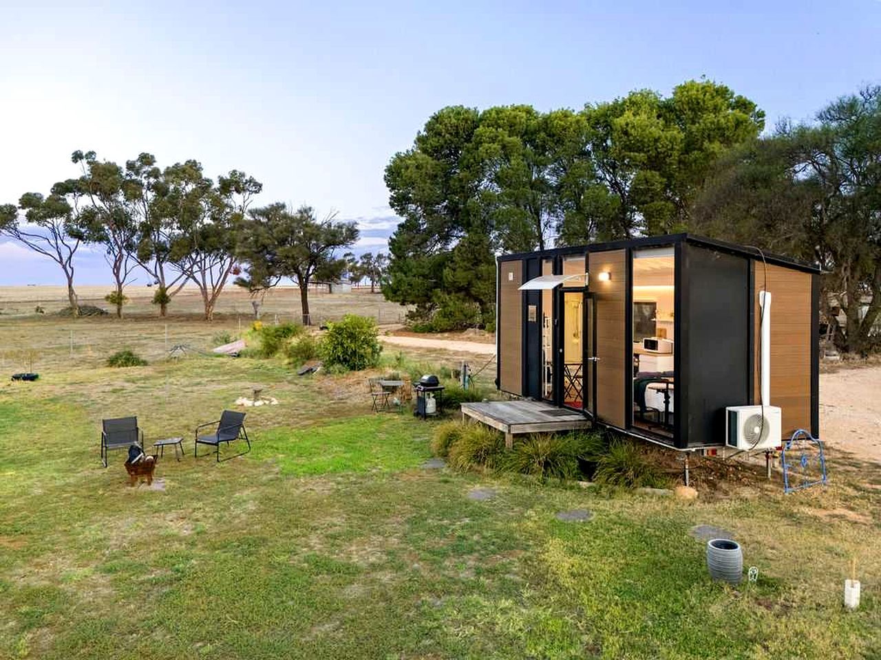 Eine moderne, kompakte Holzhütte mit Veranda und sichtbarem Innenraum mit Essbereich.