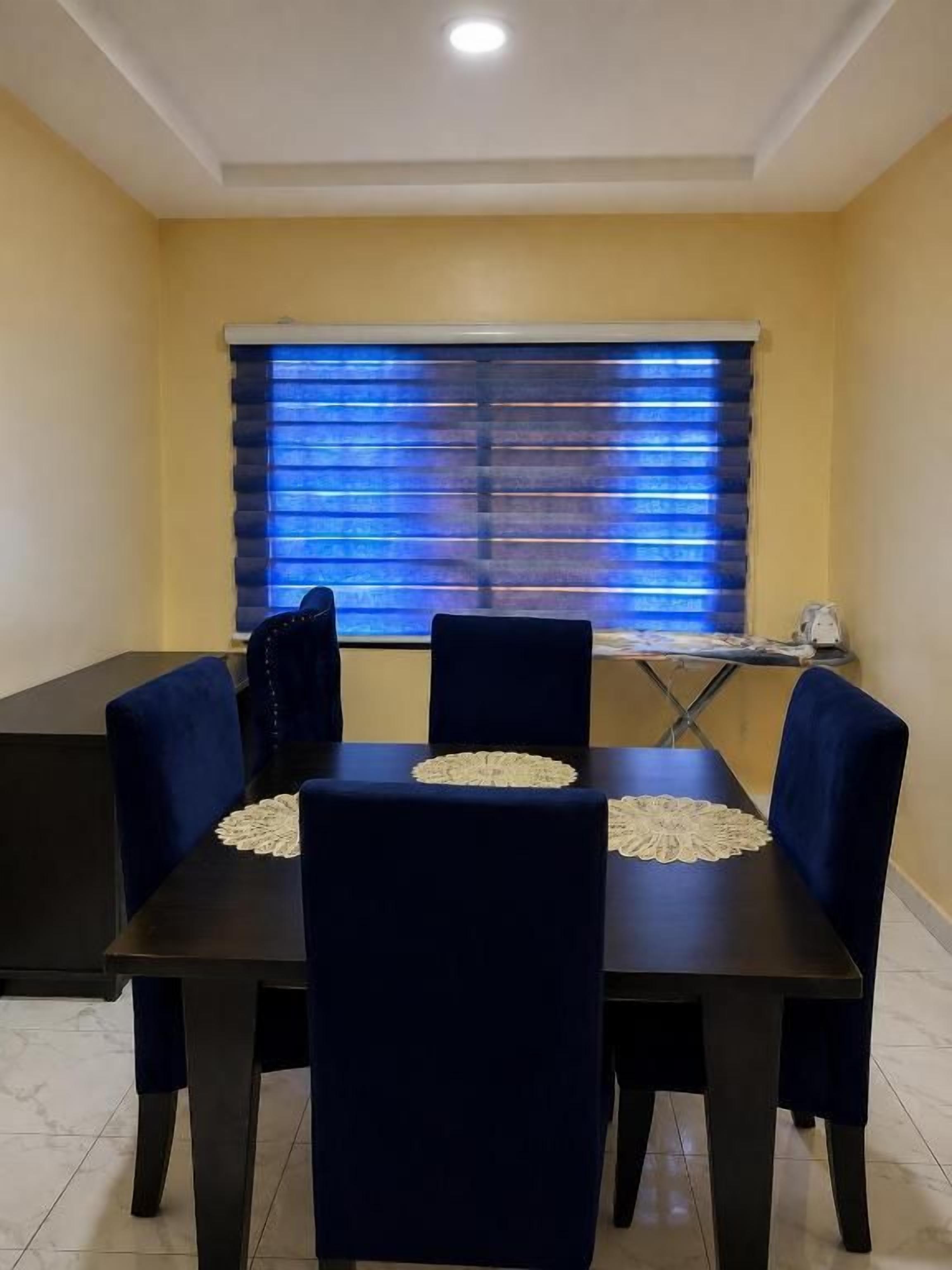 A dining area with a table and chairs, a window with blinds, and a tiled floor.