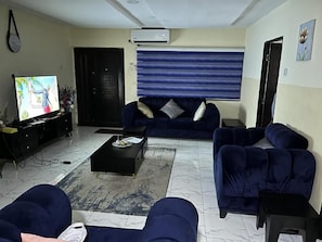 A living room with a sofa set, a coffee table, and a television. - Caligeo Suites I (Ibadan)
