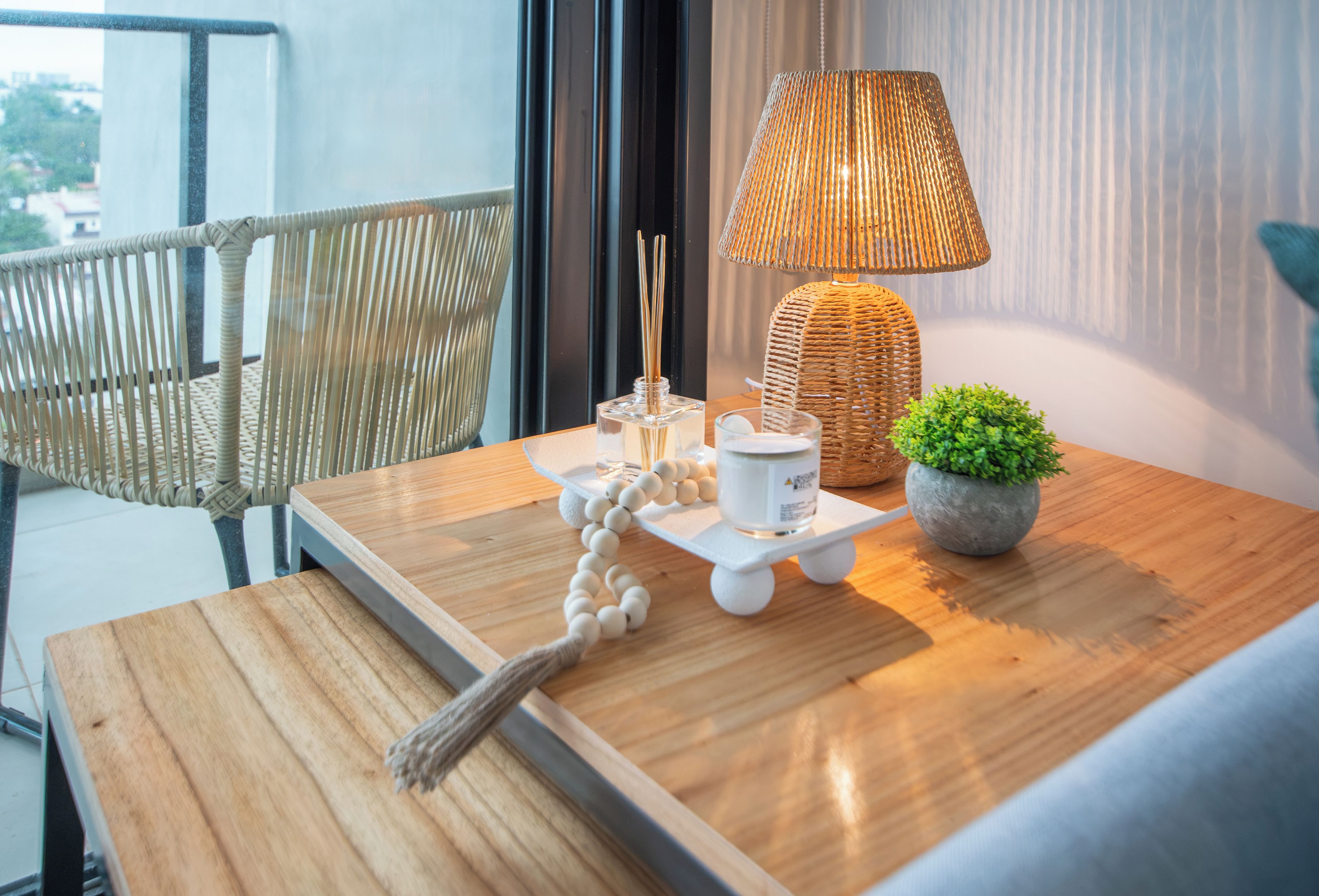 Ein Holztisch mit einer Lampe, einem kleinen Topfpflanzen, einem dekorativen Gegenstand und einem Glasbehälter.