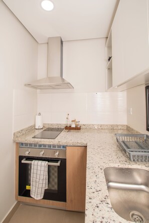 A compact kitchen with a built-in oven, a stainless steel sink, and a countertop with a speckled pattern. - Corporate Stays Matrisa - 1003 (Asunción)