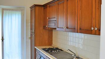 A kitchen with wooden cabinets, a gas stove, and a stainless steel sink.
