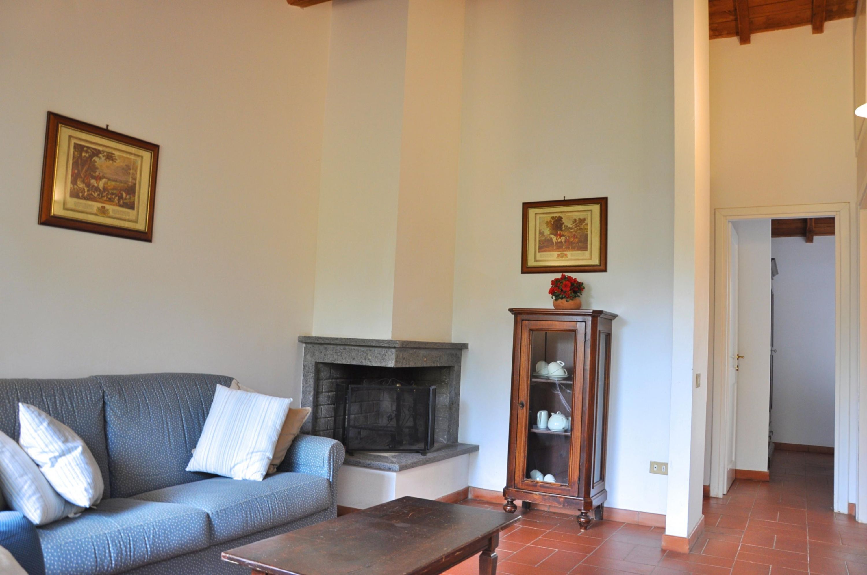 A living room with a sofa, a fireplace, and a cabinet with dishes.