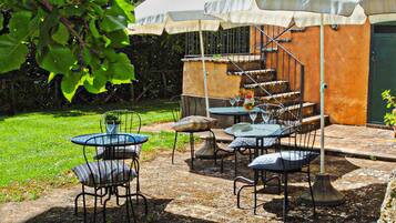 An outdoor patio with tables and chairs, a covered seating area, and a staircase leading to an upper level.