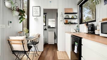 A compact kitchen with white cabinetry, a wooden countertop, and a black dishwasher.