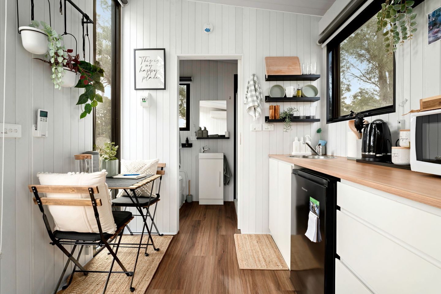 A compact kitchen with white cabinetry, a wooden countertop, and a black dishwasher.