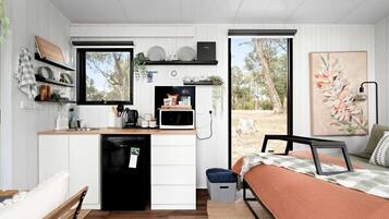 A compact kitchen with a microwave, sink, and storage shelves.