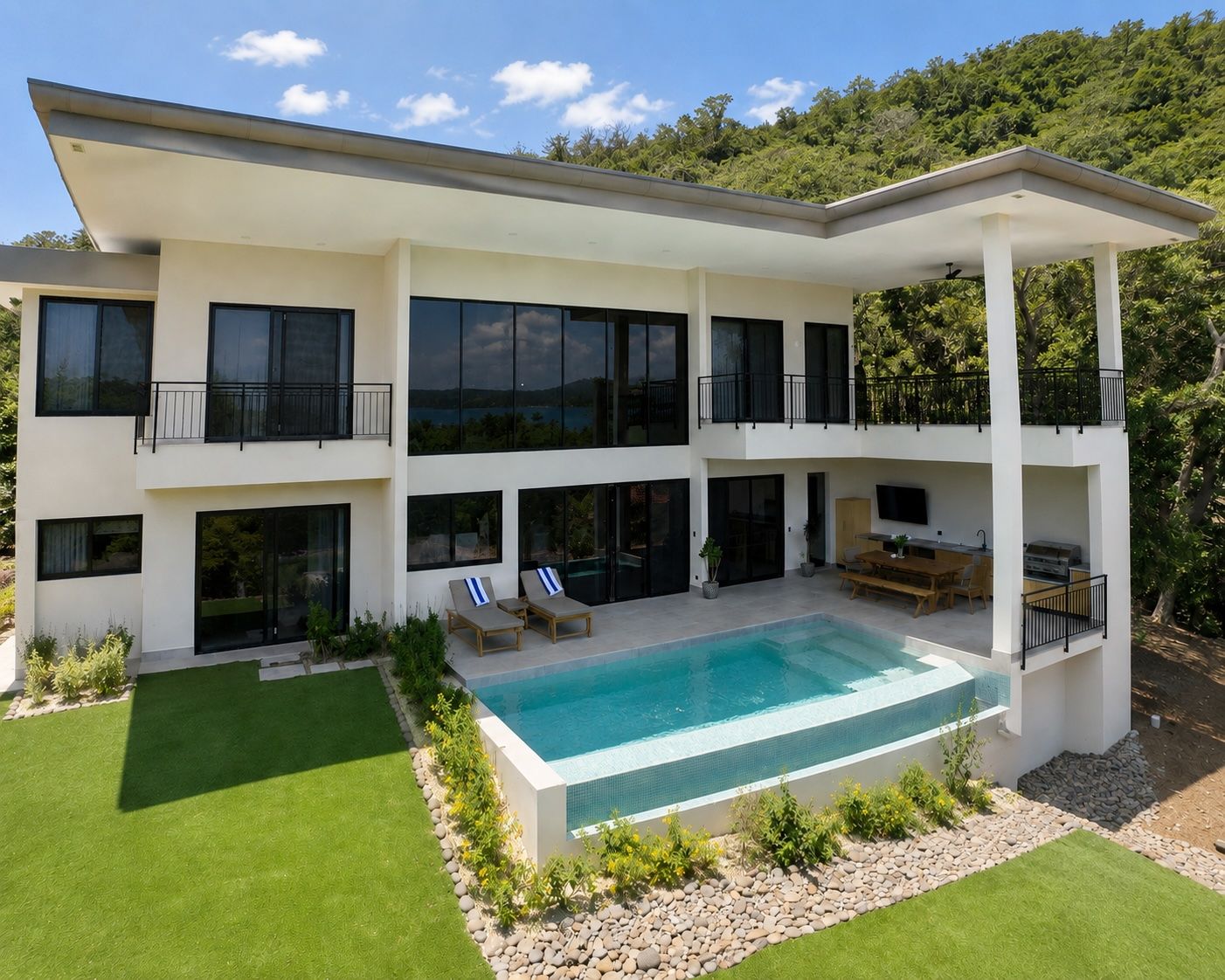 A modern two-story house with a swimming pool, outdoor seating, and a balcony.