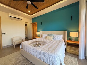 A bedroom with a bed, nightstands, a chair, and a ceiling fan. - Casa Pura Aventura | Pool, Views & Coastal Luxury (Playa Hermosa)