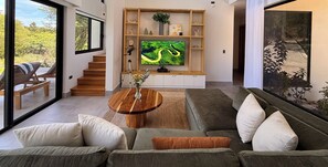 A modern living room with a sofa, a coffee table, and a television. - Casa Pura Aventura | Pool, Views & Coastal Luxury (Playa Hermosa)