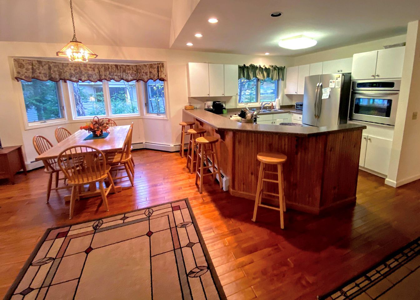 Una cocina moderna con una isla de madera, taburetes de bar y un comedor con sillas.