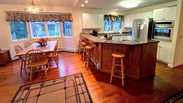 Una cocina moderna con una isla de madera, taburetes de bar y un comedor con sillas.