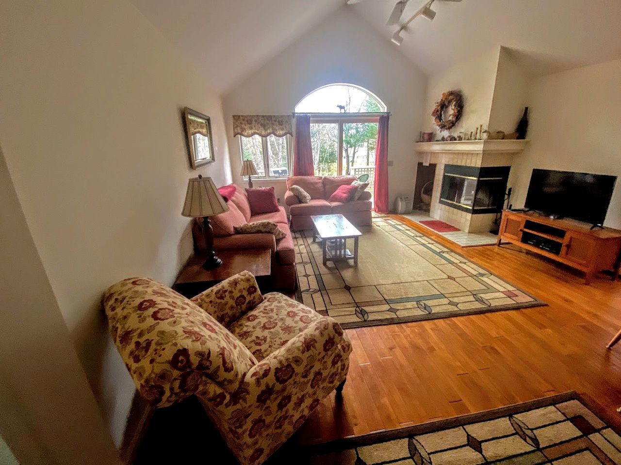 Una sala de estar con chimenea, televisión y un ventanal grande.