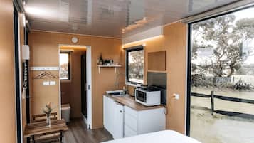 Una habitación compacta con cama, kitchenette, ventana y vista al exterior.