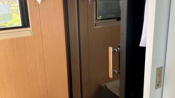 A bathroom with a glass shower enclosure, a toilet, and a window.