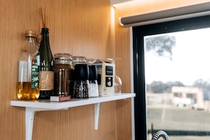 A shelf with various kitchen items including a bottle of olive oil, a jar of spices, and a container of Camomile tea.