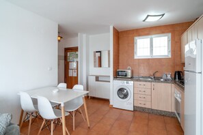 A compact kitchen with a washing machine, microwave, and refrigerator. - Apartment in Nerja by Torrecilla Beach (Nerja)