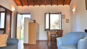A room with a wooden ceiling, a dining table with chairs, a sofa, and a cabinet.