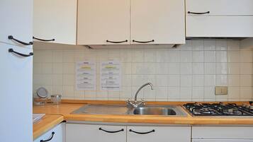 A kitchen with white cabinets, a stainless steel sink, a gas stove, and a wooden countertop.