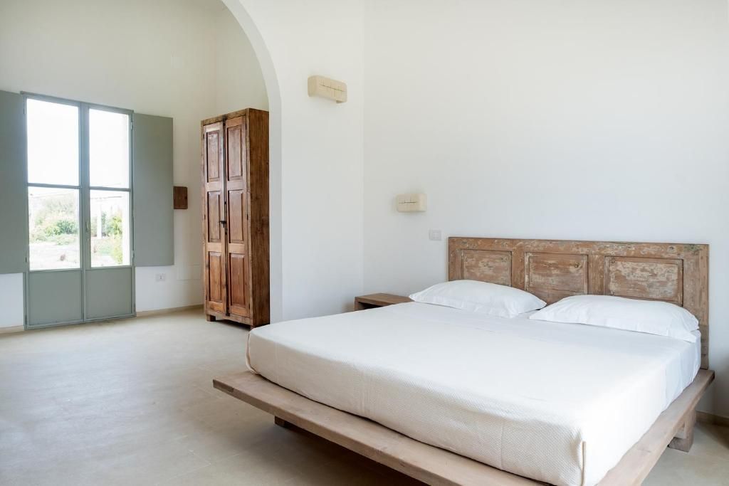 A bedroom with a bed, wooden headboard, and a wardrobe.