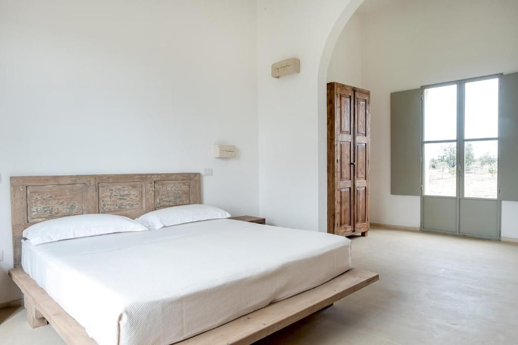 A bedroom with a wooden bed frame, a large window, and a wooden wardrobe.