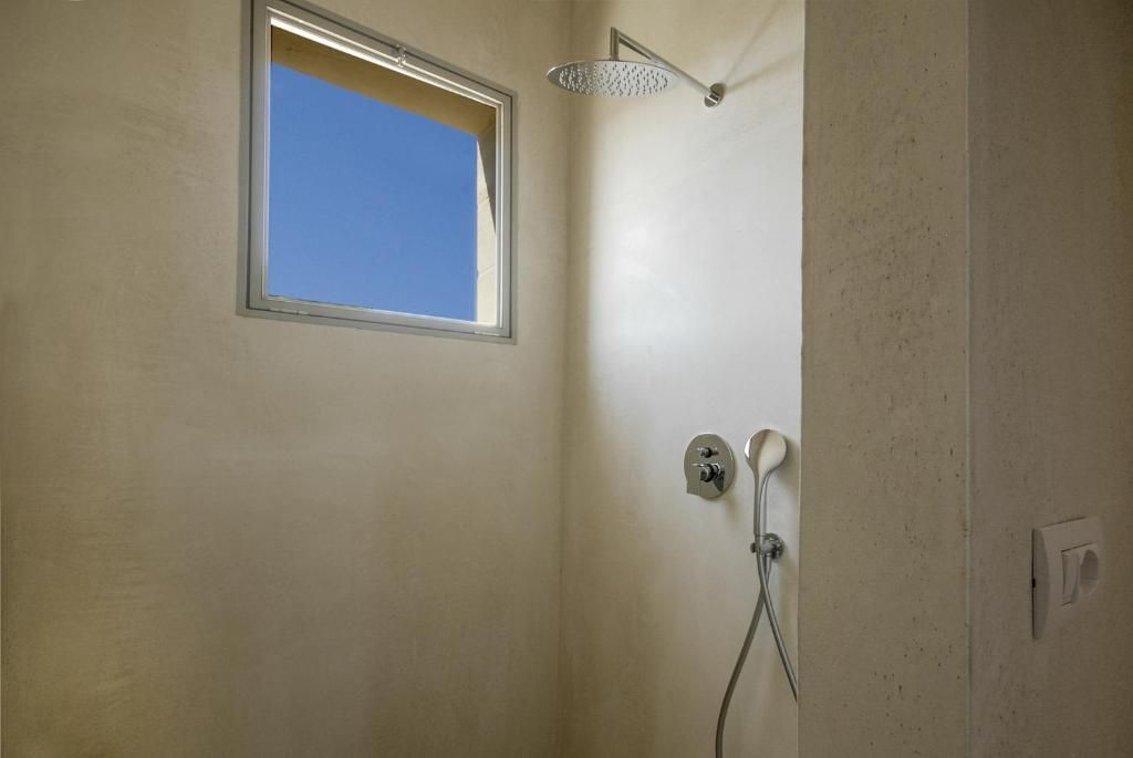 A bathroom with a shower, a window, and a wall-mounted light fixture.