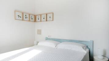 A neatly made bed with a patterned bedspread, a wooden headboard, and a bedside table with a lamp.