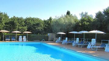 A swimming pool with lounge chairs and umbrellas.