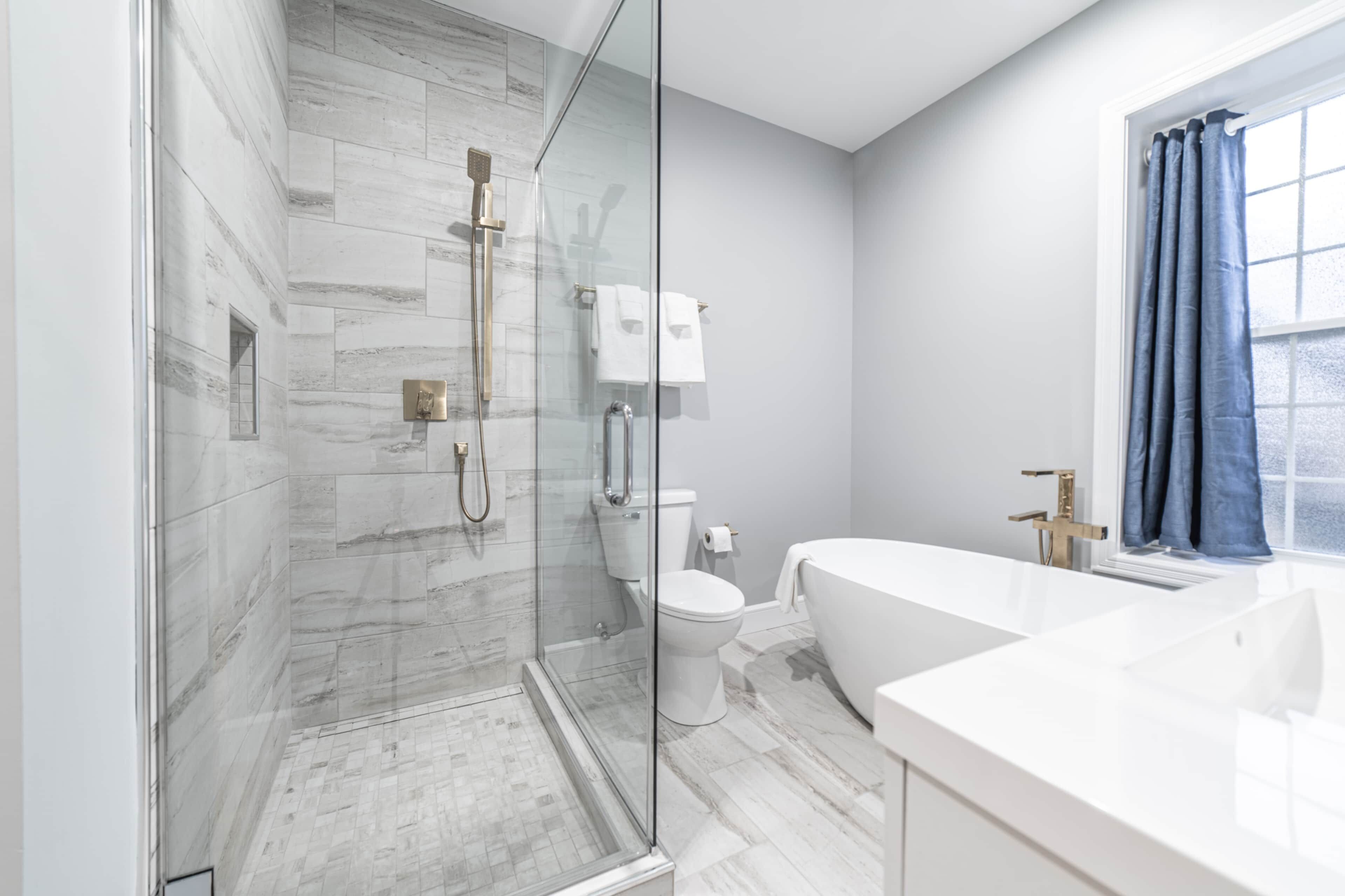 A modern bathroom with a glass-enclosed shower, a toilet, and a bathtub.
