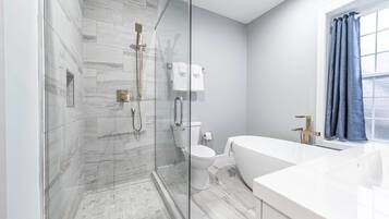 A modern bathroom with a glass-enclosed shower, a toilet, and a bathtub.