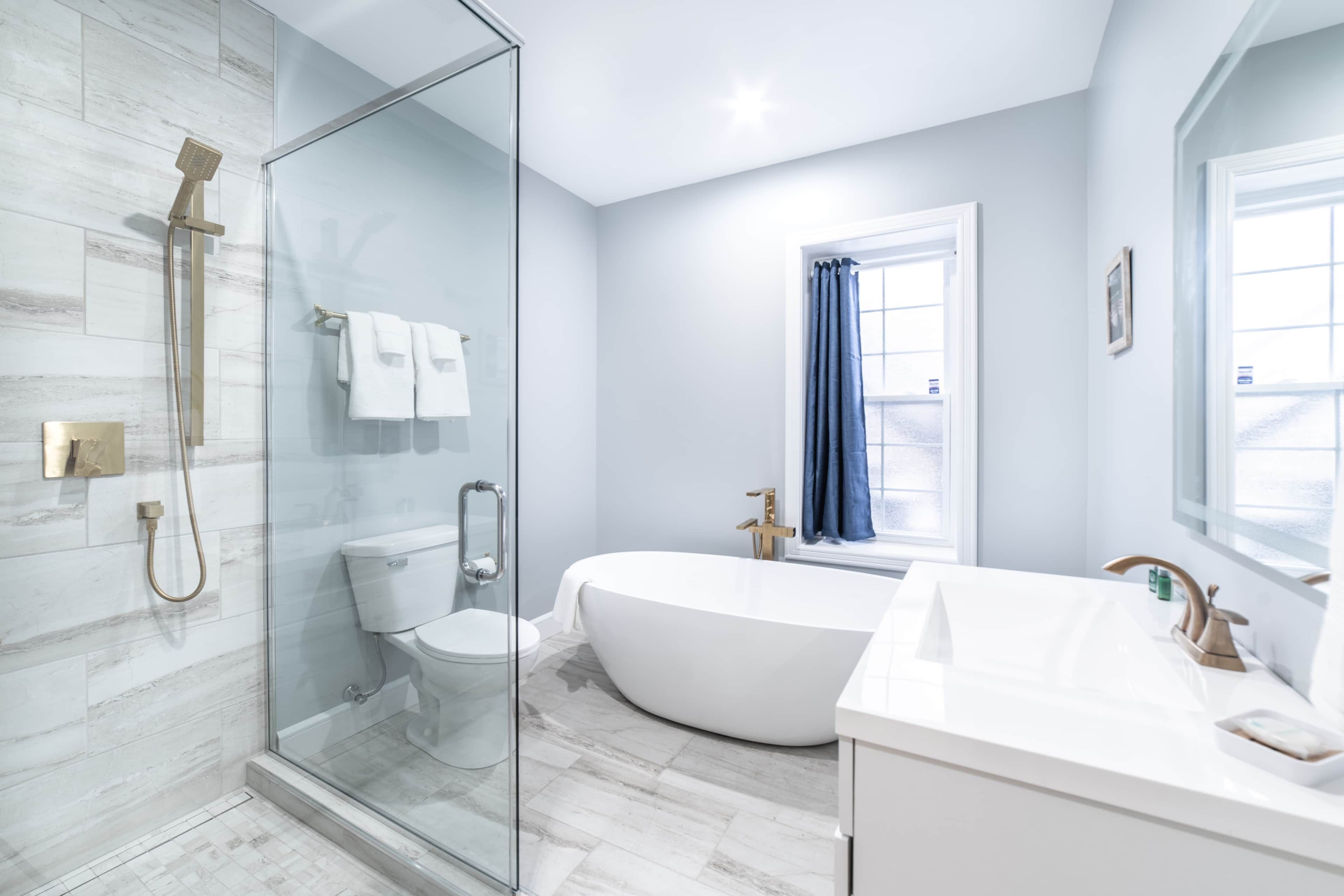 A modern bathroom with a glass shower enclosure, a freestanding bathtub, and a vanity with a sink.