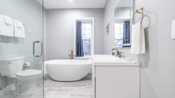 Une salle de bain moderne avec une baignoire sur pieds, des toilettes et un lavabo.