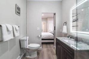 Une salle de bain moderne équipée de toilettes, d’un lavabo et d’une douche à parois en verre.