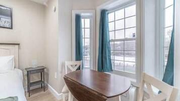 Quarto de hotel com cama, uma mesa de madeira e janela com cortinas.