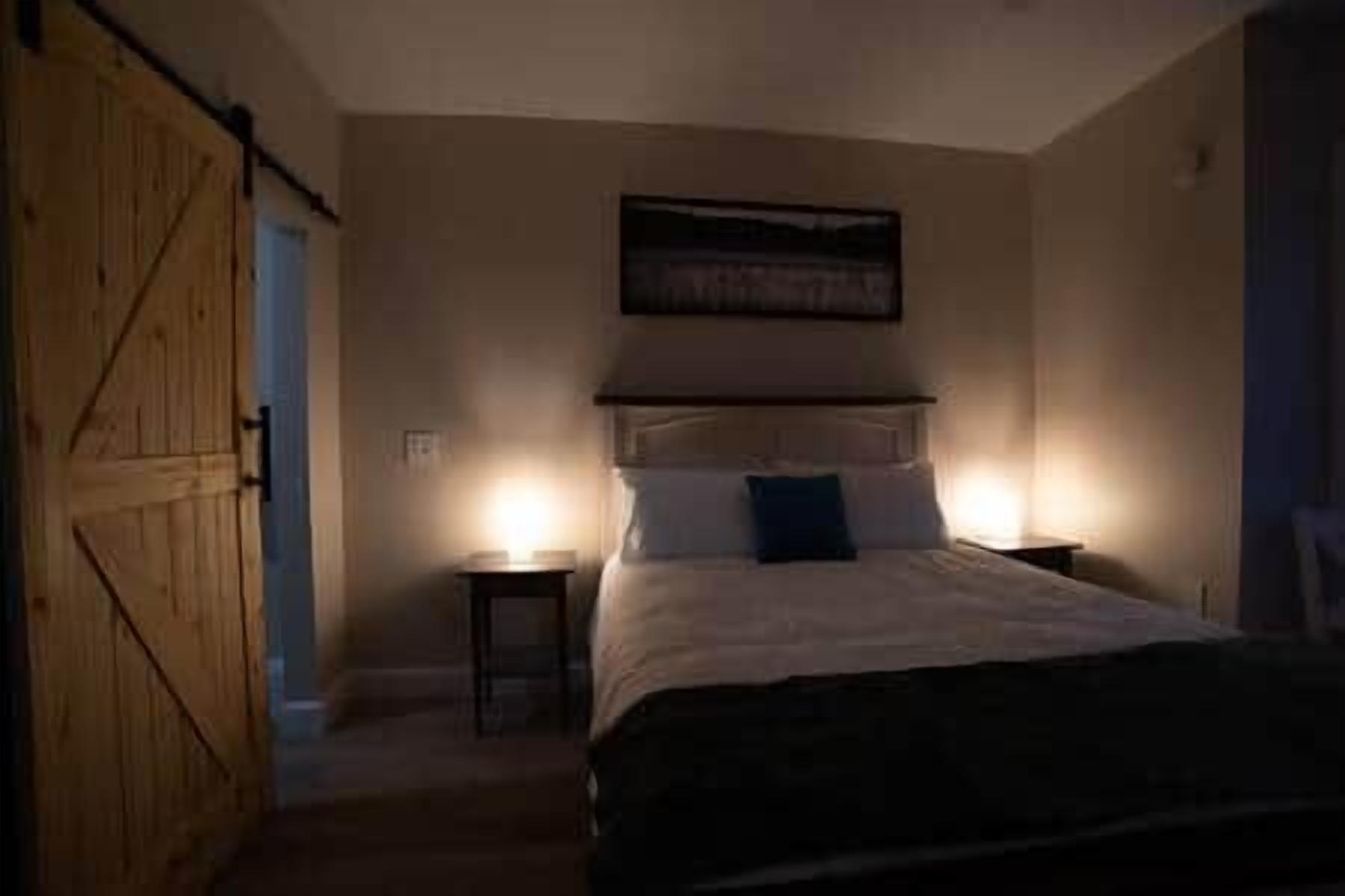 A bedroom with a bed, bedside tables, and a door.
